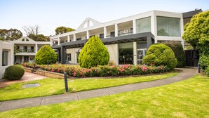A modern building with multiple floors, large windows, and a well-maintained garden with various plants and flowers. - Nightelier Doncaster (Doncaster)