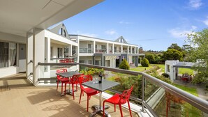 A balcony with red chairs and a table, overlooking a garden and a building with multiple balconies. - Nightelier Doncaster (Doncaster)