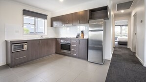 A modern kitchen with dark wood cabinets, stainless steel appliances, and a large window. - Nightelier Doncaster (Doncaster)