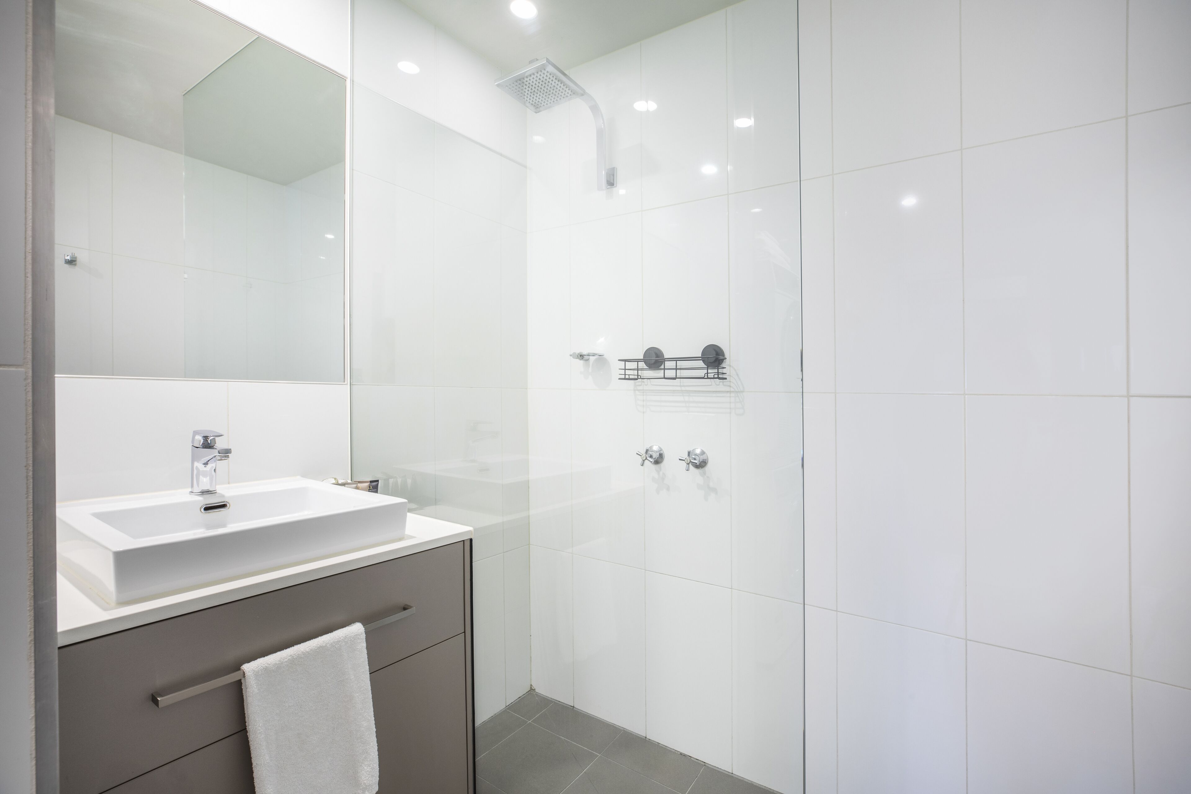 A modern bathroom with a white sink, mirror, and shower.