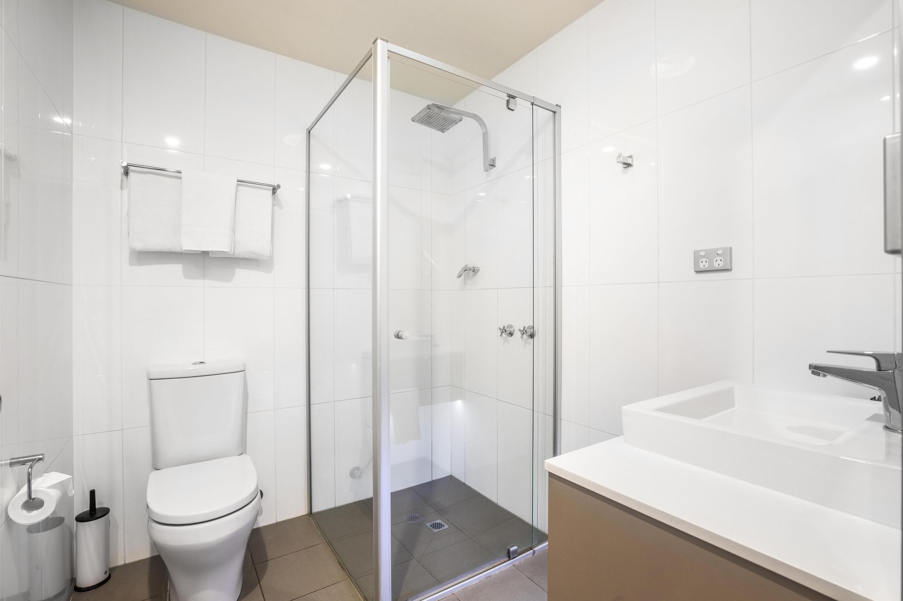 A modern bathroom with a glass-enclosed shower, a white toilet, and a large bathtub.