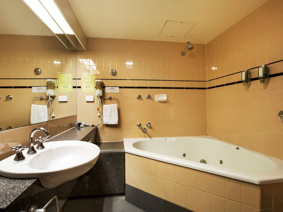 A hotel bathroom with a sink, mirror, and bathtub.