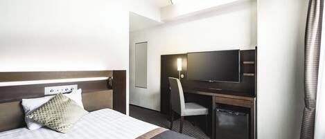 Een hotelkamer met een bed, een bureau met een televisie, een stoel en een kledingkast.