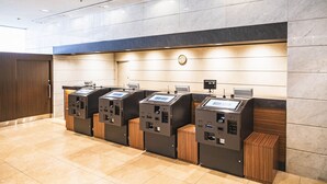 A row of self-service kiosks with a digital interface, a clock, and a wooden cabinet on the right. - Hotel new Hankyu Osaka Annex (Osaka)
