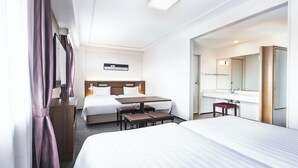 A hotel room with two beds, a desk, a chair, a small table, a mirror, and a bathroom with a sink and mirror. - Hotel new Hankyu Osaka Annex (Osaka)