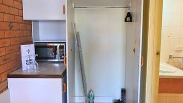 Une pièce compacte comprenant un coin cuisine, une douche et un petit espace de rangement.