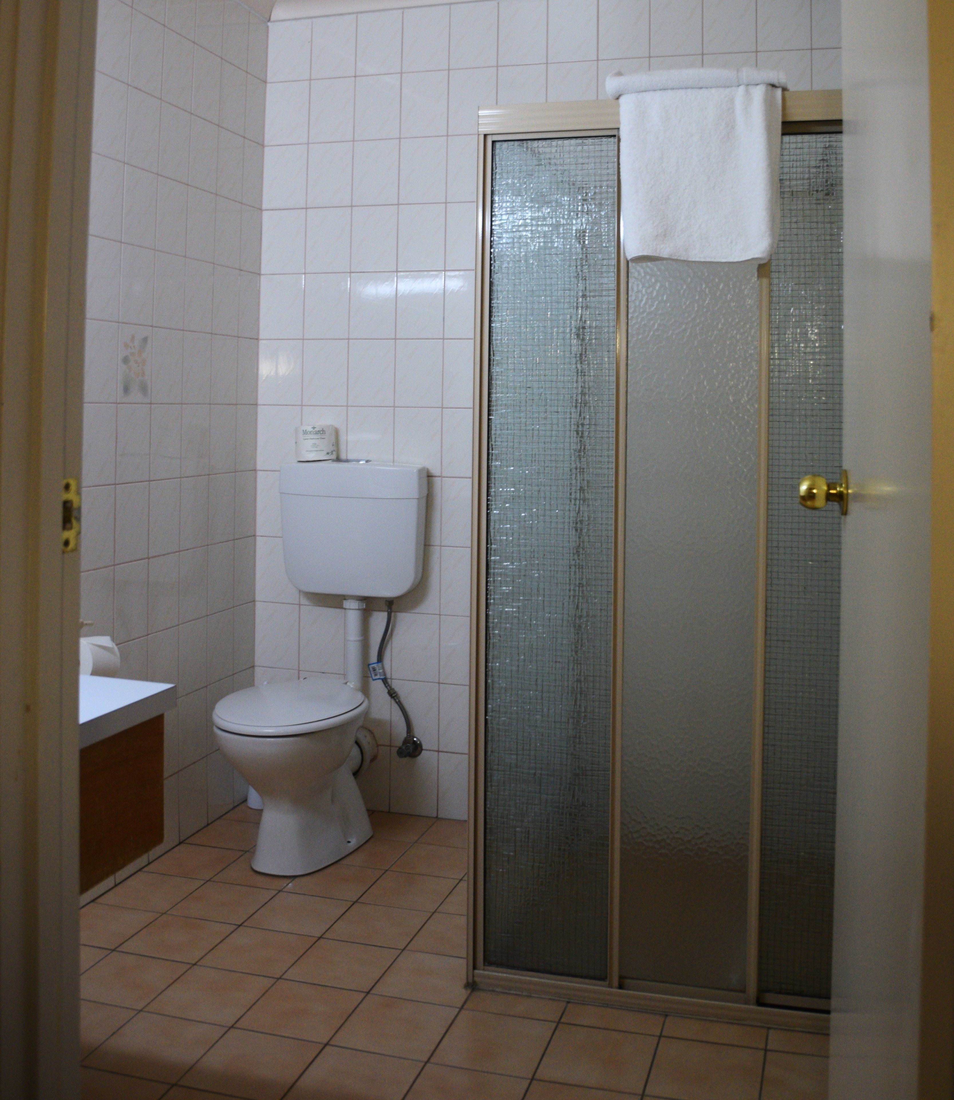 A bathroom with a toilet, a shower enclosure, and a sink.