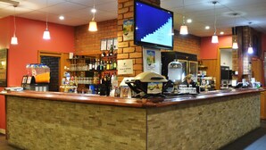A bar area with a counter, shelves with bottles, a television screen, and hanging lights. - Peppermill Inn (Kialla)