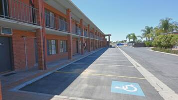 A row of brick buildings with a parking lot in front, including a handicapped parking space.