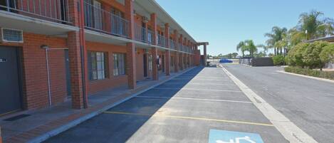 Una hilera de edificios de ladrillo con un estacionamiento al frente, incluyendo un espacio reservado para discapacitados.
