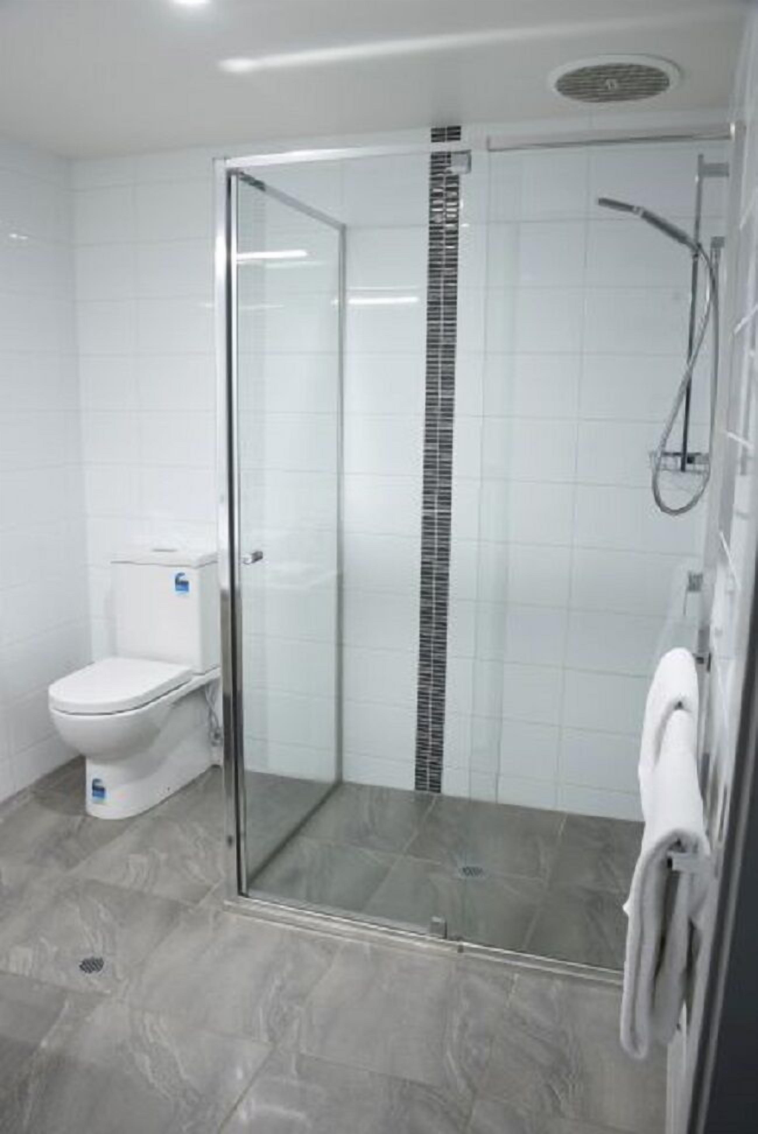 Ein modernes Badezimmer mit einer gläsernen Duschkabine, einer Toilette und einem Handtuchhalter.