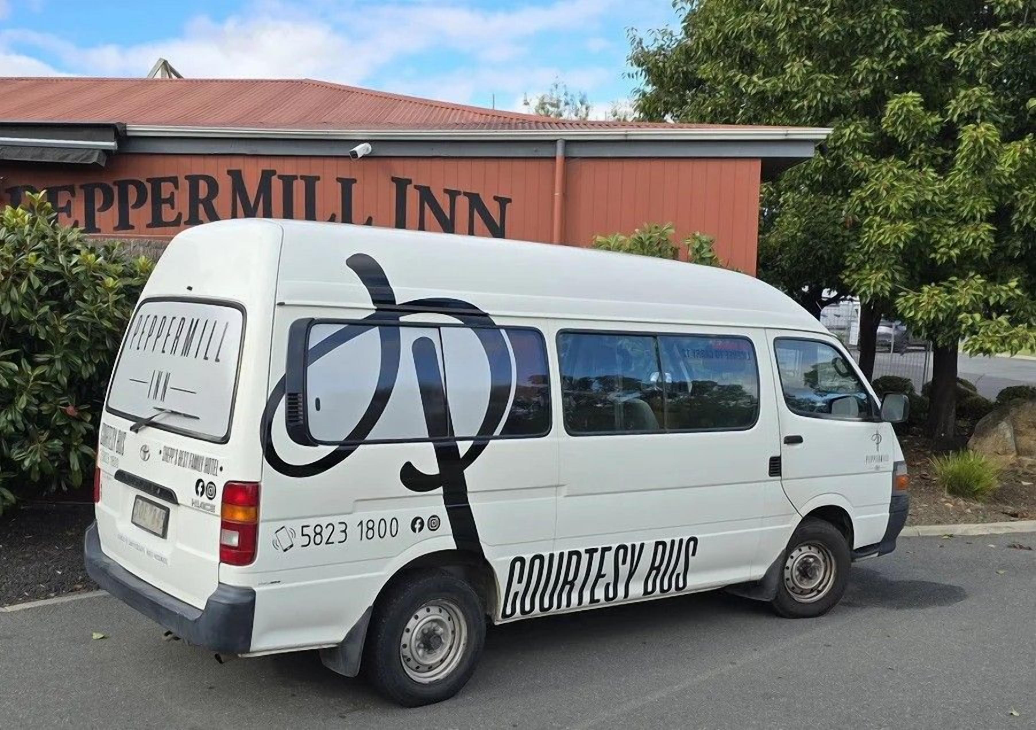 Una camioneta blanca estacionada frente a un edificio con el letrero 'Peppermill Inn'.