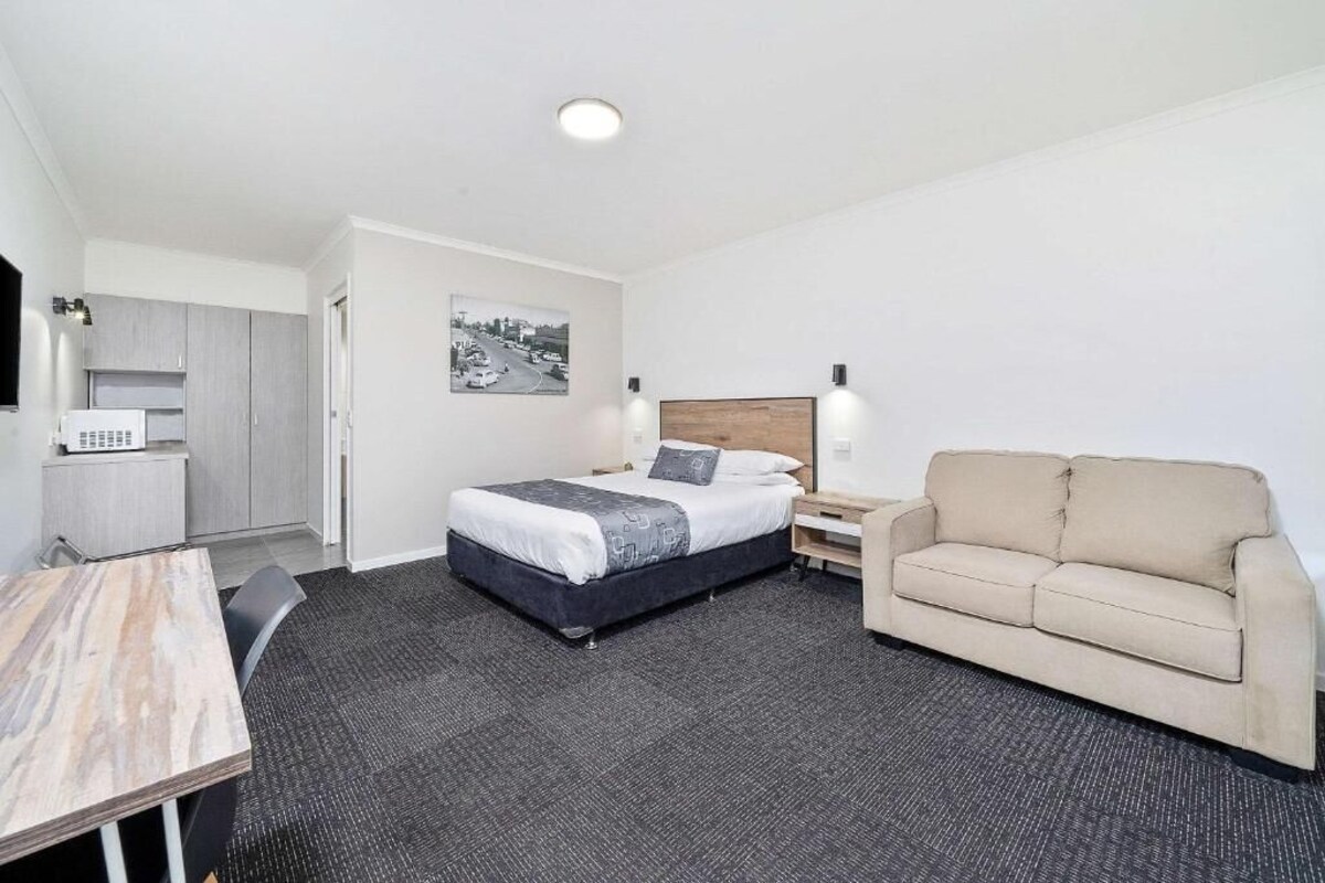 A hotel room with a bed, a sofa, a desk, and a chair.