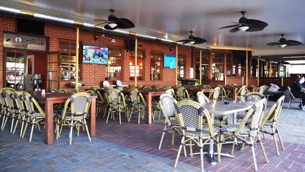 A restaurant with brick walls, multiple ceiling fans, and wicker chairs. - Peppermill Inn (Kialla)