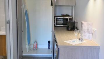 Una cocina compacta con microondas, una pequeña encimera y un armario.