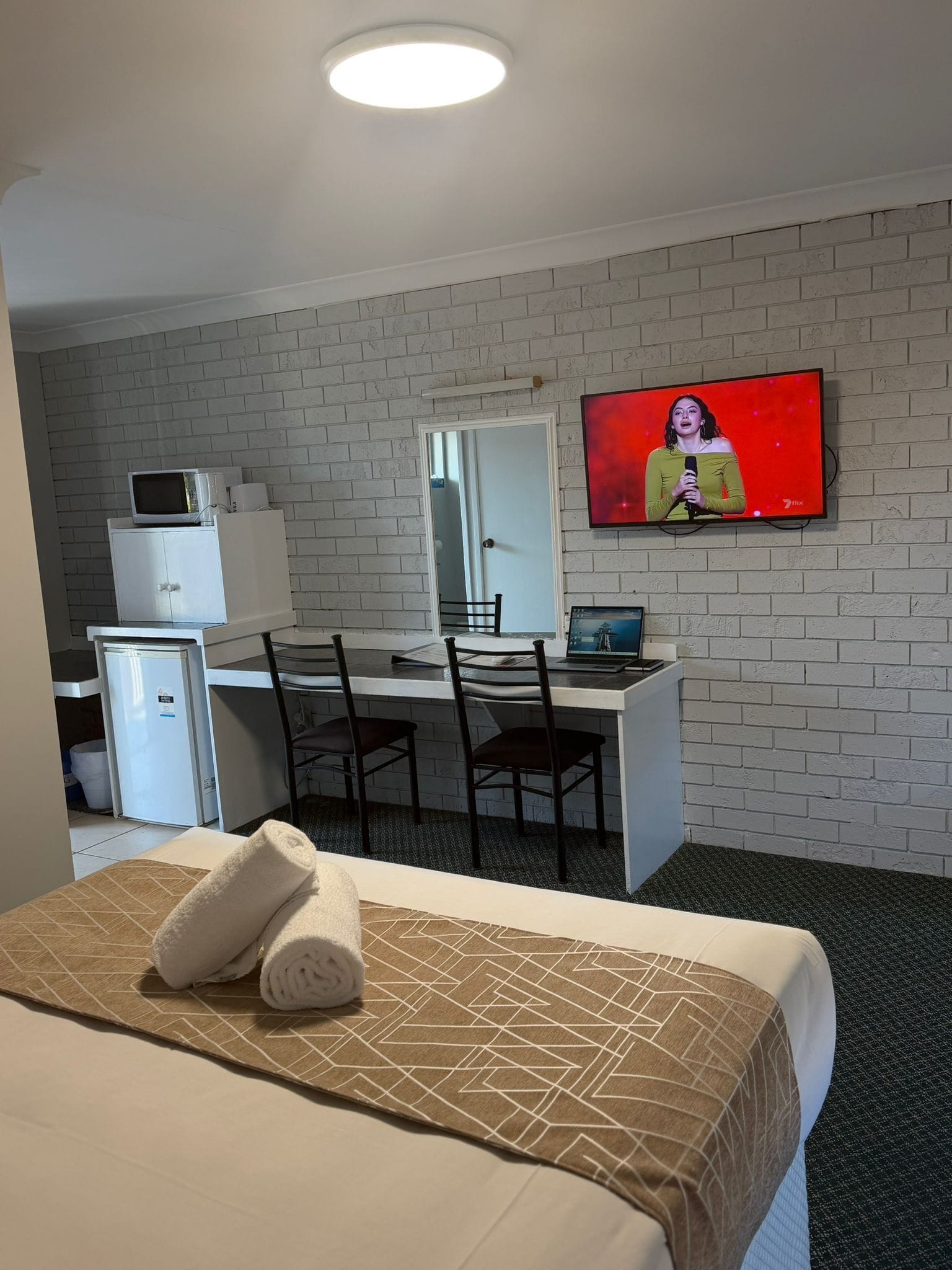 Een hotelkamer met een bed, een bureau, een televisie en een koelkast.