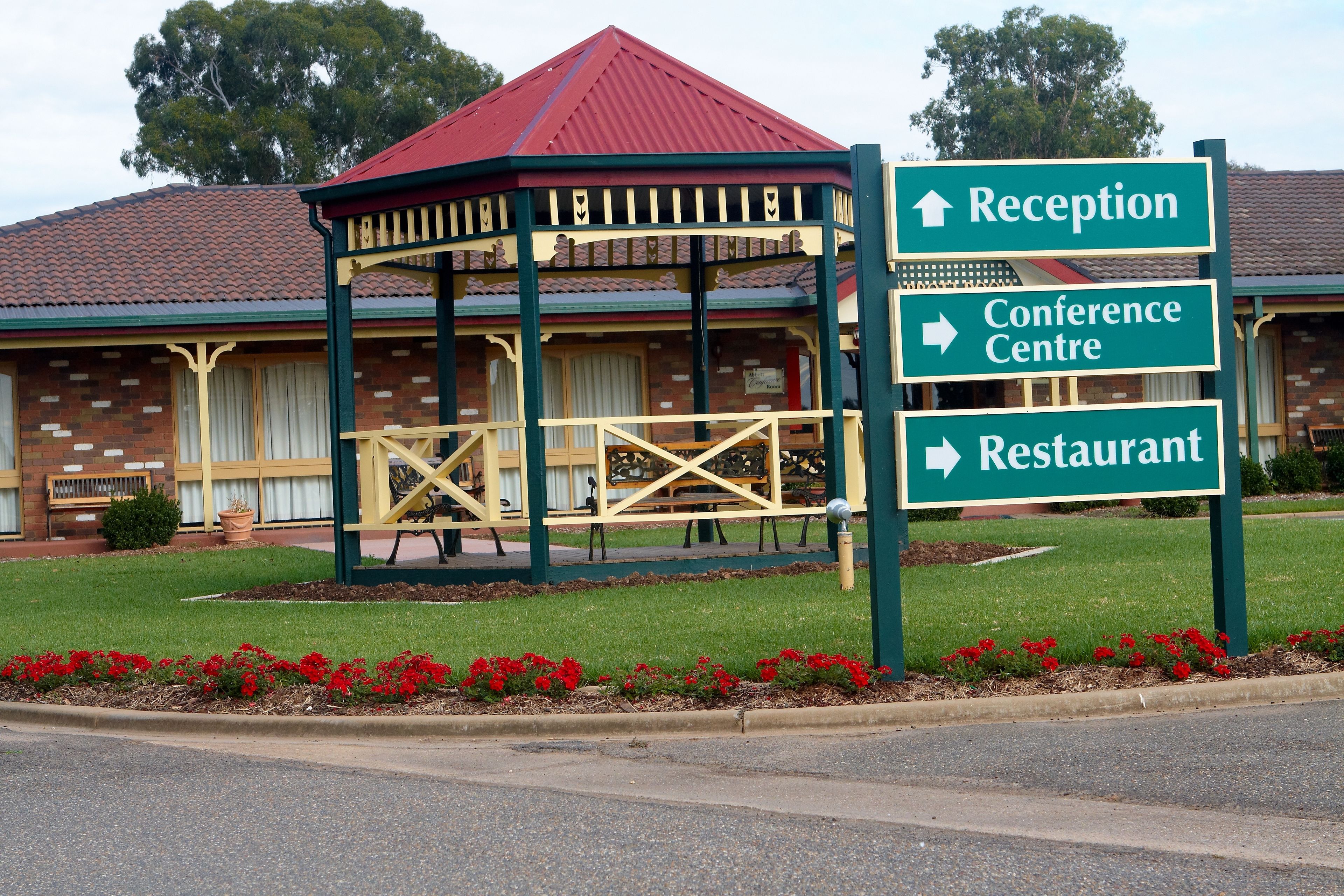 A building with a red-roofed pavilion, a reception sign, a conference center sign, and a restaurant sign.