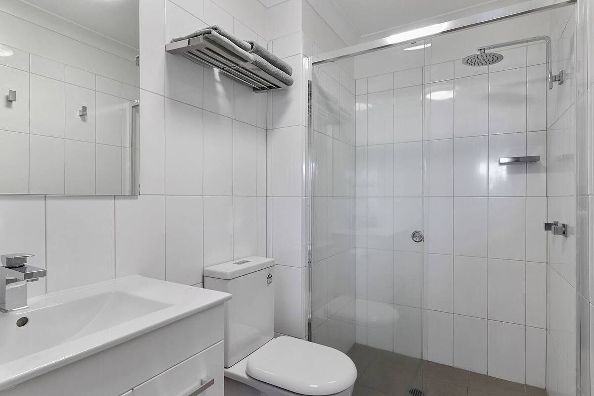 A modern bathroom with a toilet, sink, and shower.