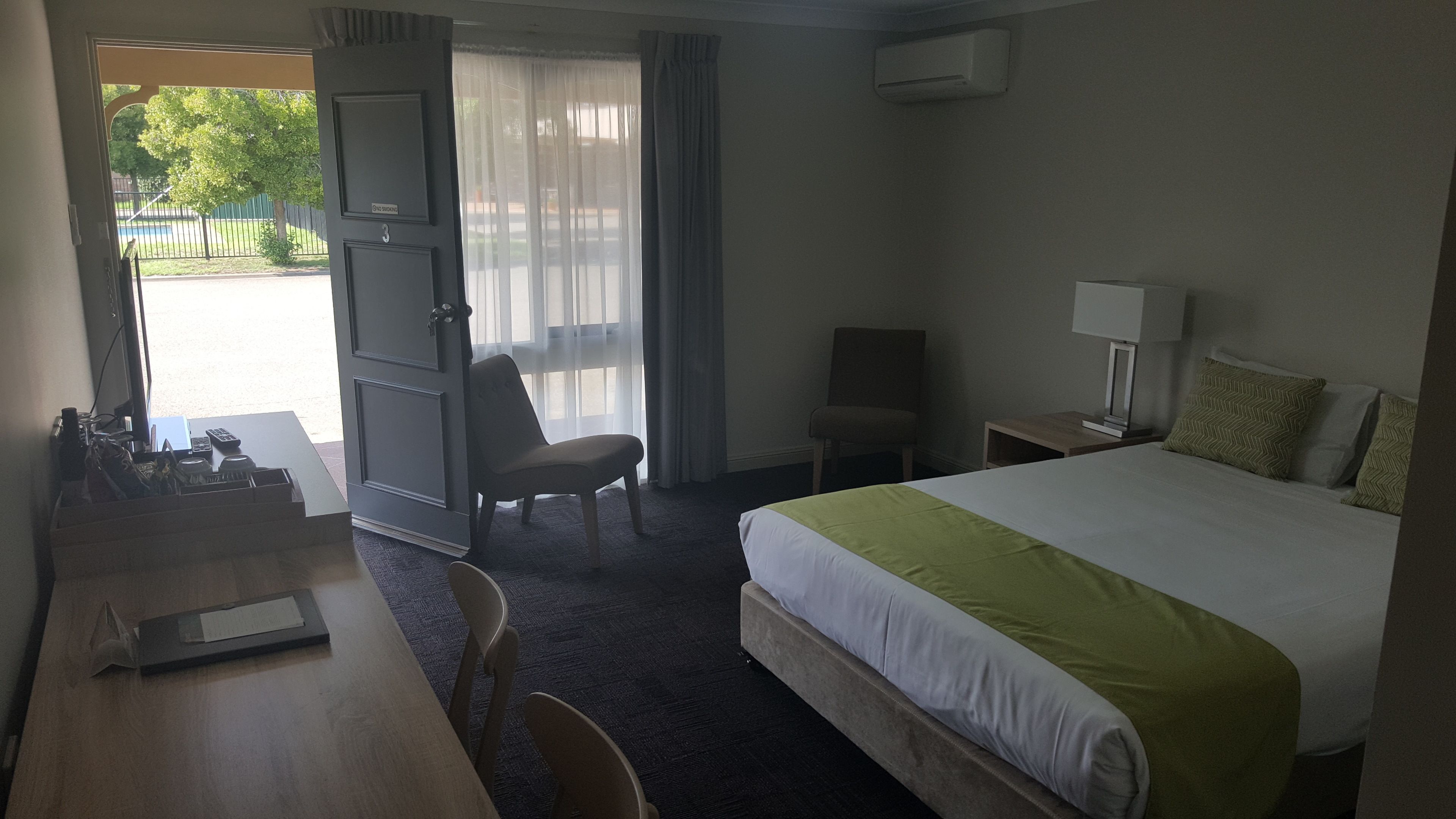 Hotellihuone, jossa on sänky, työpöytä, tuoli ja näkymä ulos.