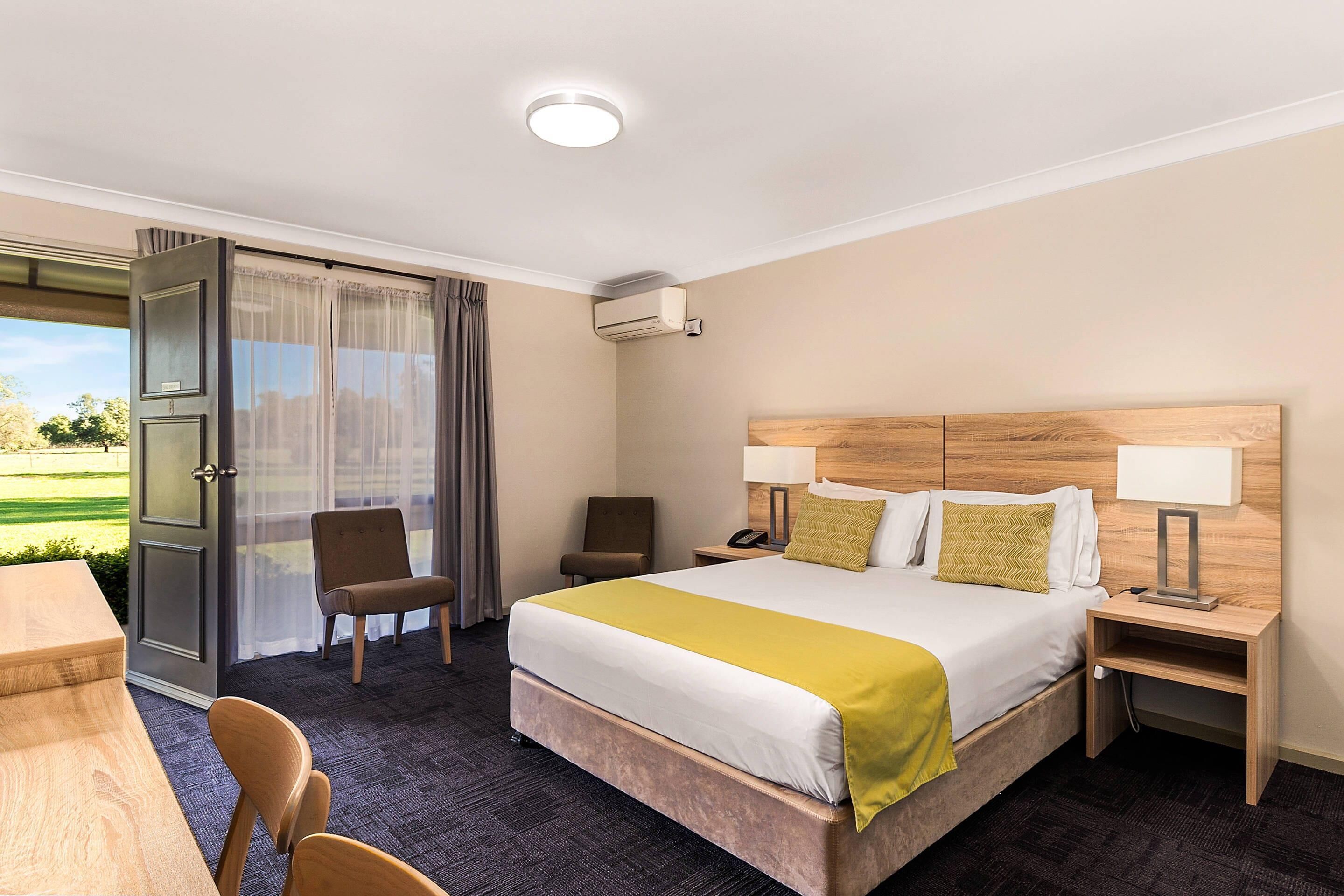 A hotel room with a bed, bedside tables, a desk, and a chair.