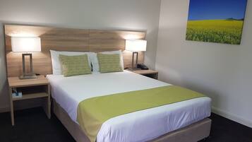 A hotel room with a bed, two bedside tables, two lamps, a telephone, and a painting on the wall.