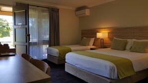 Habitación de hotel con dos camas, un escritorio y una silla.