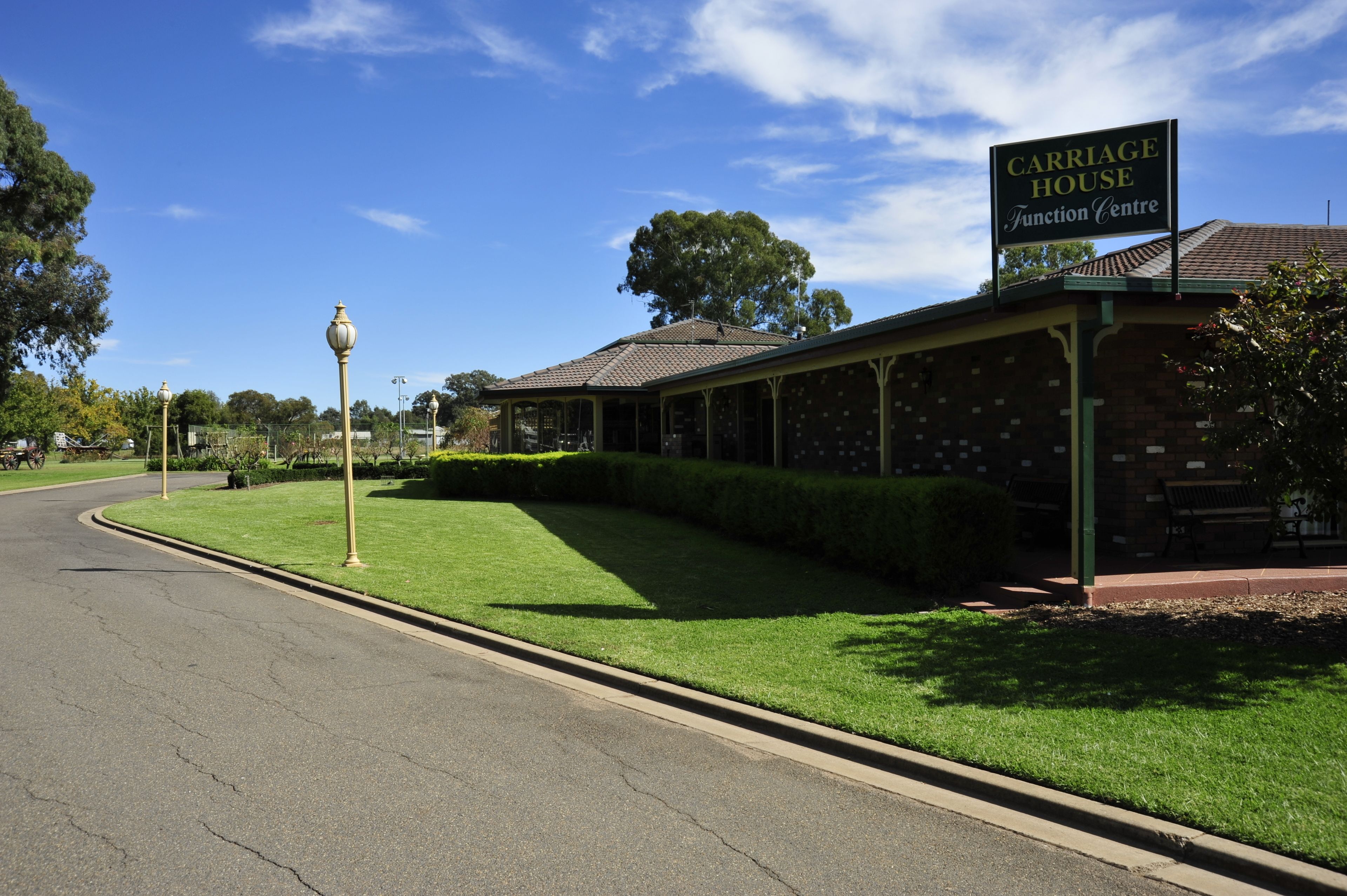 A carriage house with a sign reading "Carriage House Function Centre" under a clear blue sky.