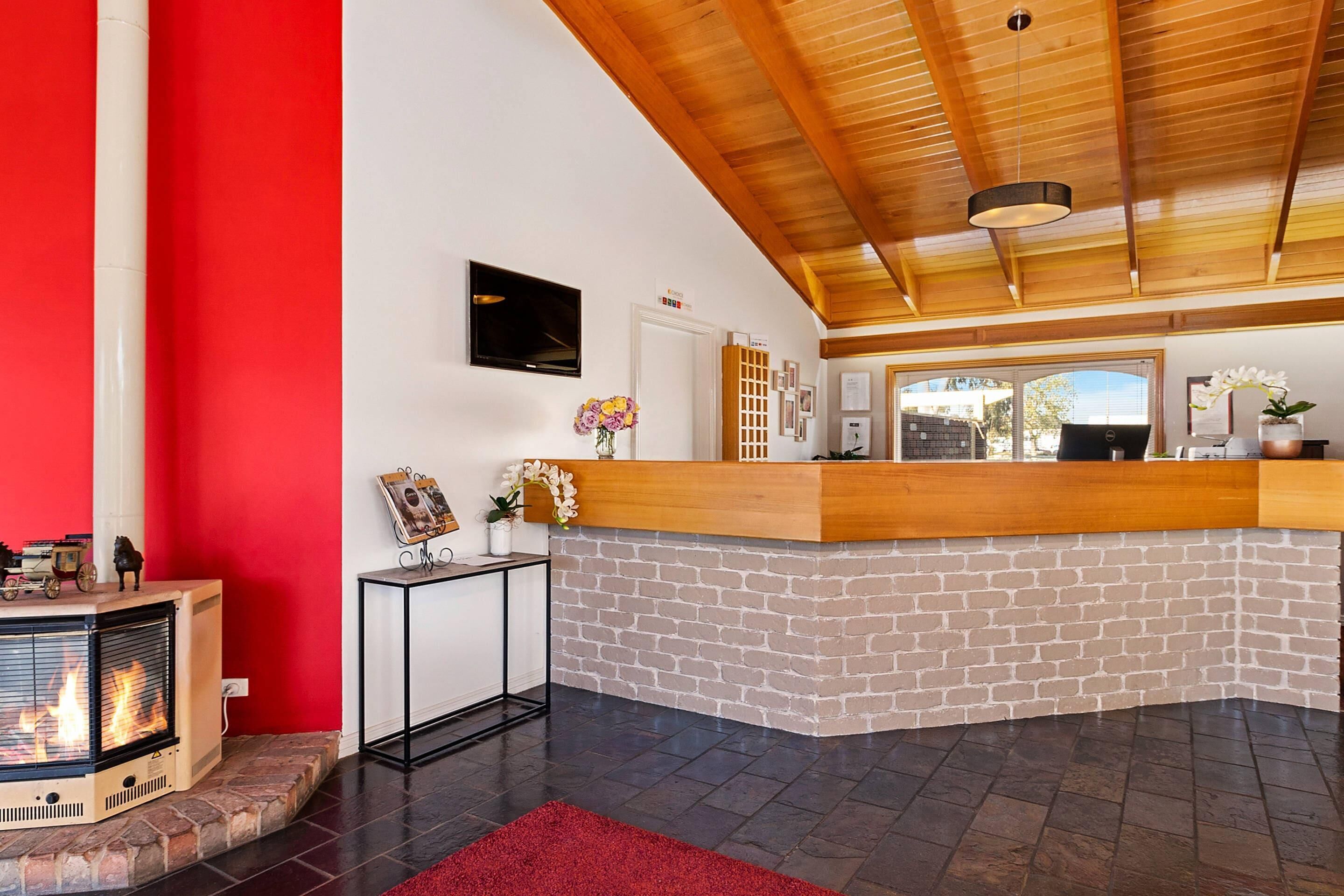 Ein modernes Interieur mit Kamin, einer Rezeption und einer Holzbalkendecke.