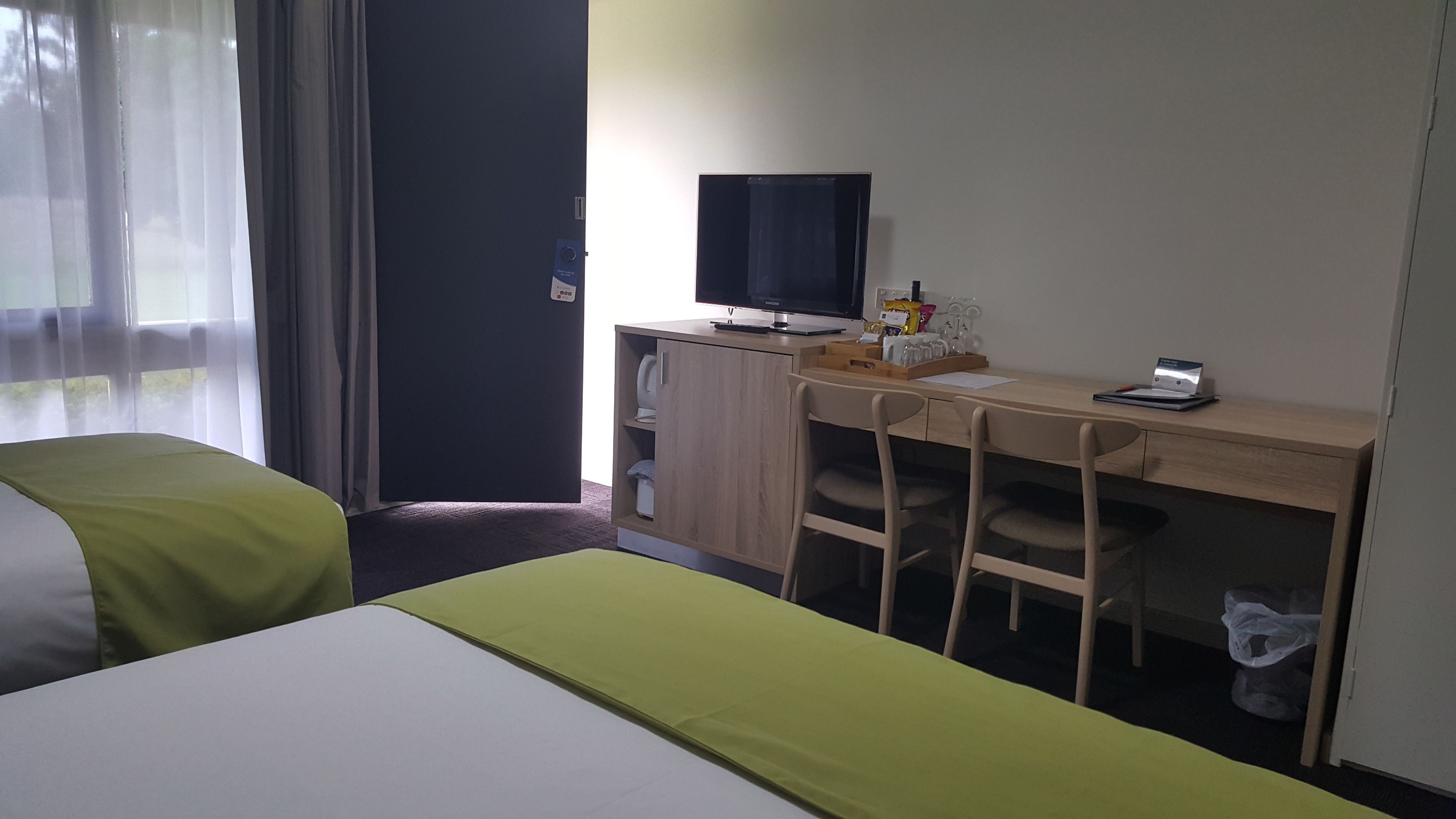 A hotel room with a bed, a desk with a computer, a television, and a chair.