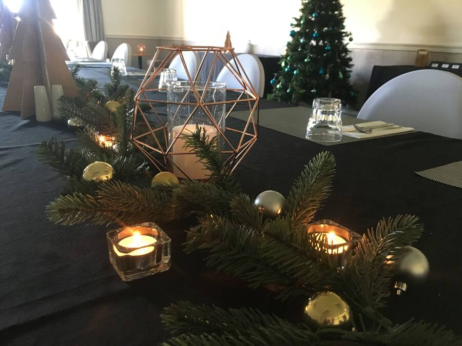 Una mesa vestida con mantel negro, velas y adornos navideños.