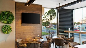 A modern restaurant with wooden walls, a flat-screen TV, wicker chairs, and a view of the street. - Quality Hotel Wangaratta Gateway (Wangaratta)
