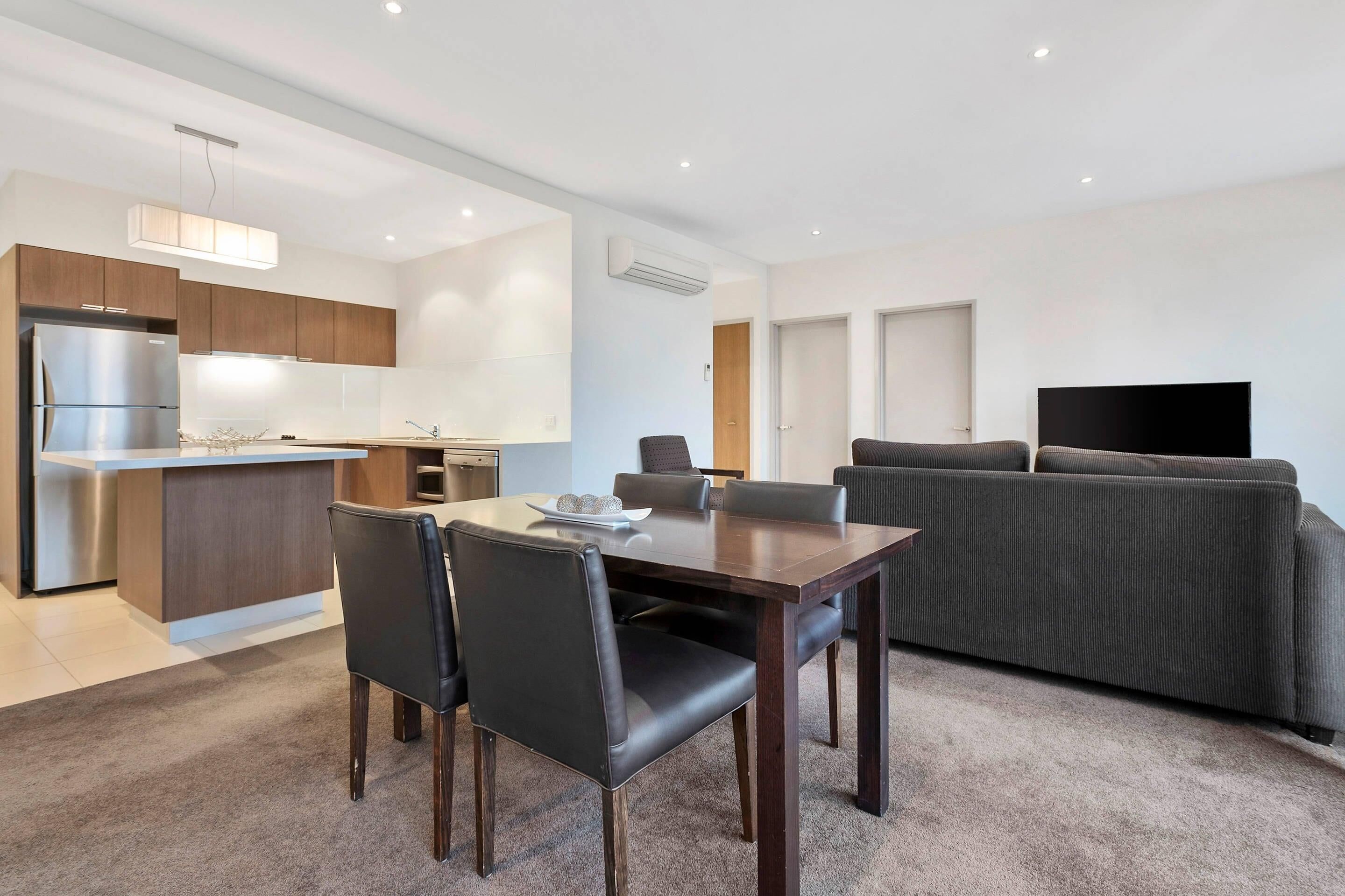A modern apartment with a dining area, kitchen, and living space.