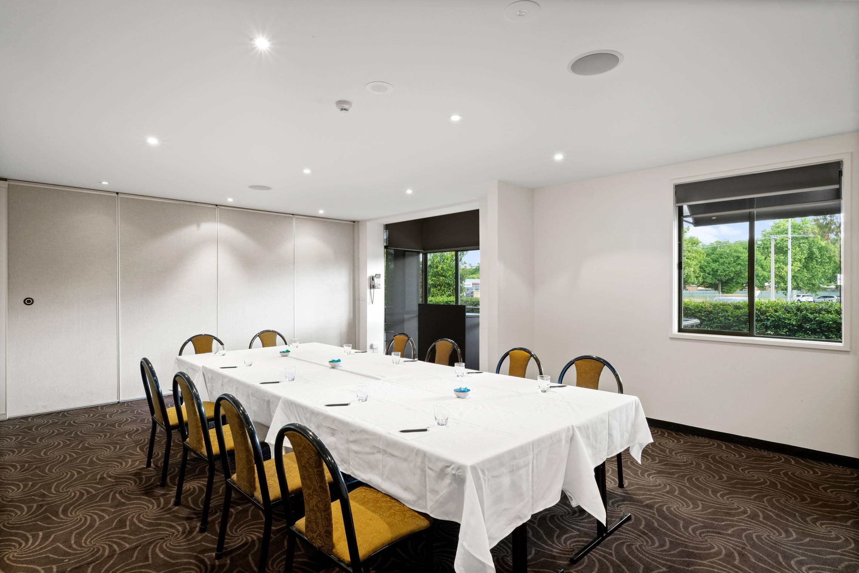A conference room with a long table, chairs, and a large window.