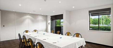 A conference room with a long table, chairs, and a large window.