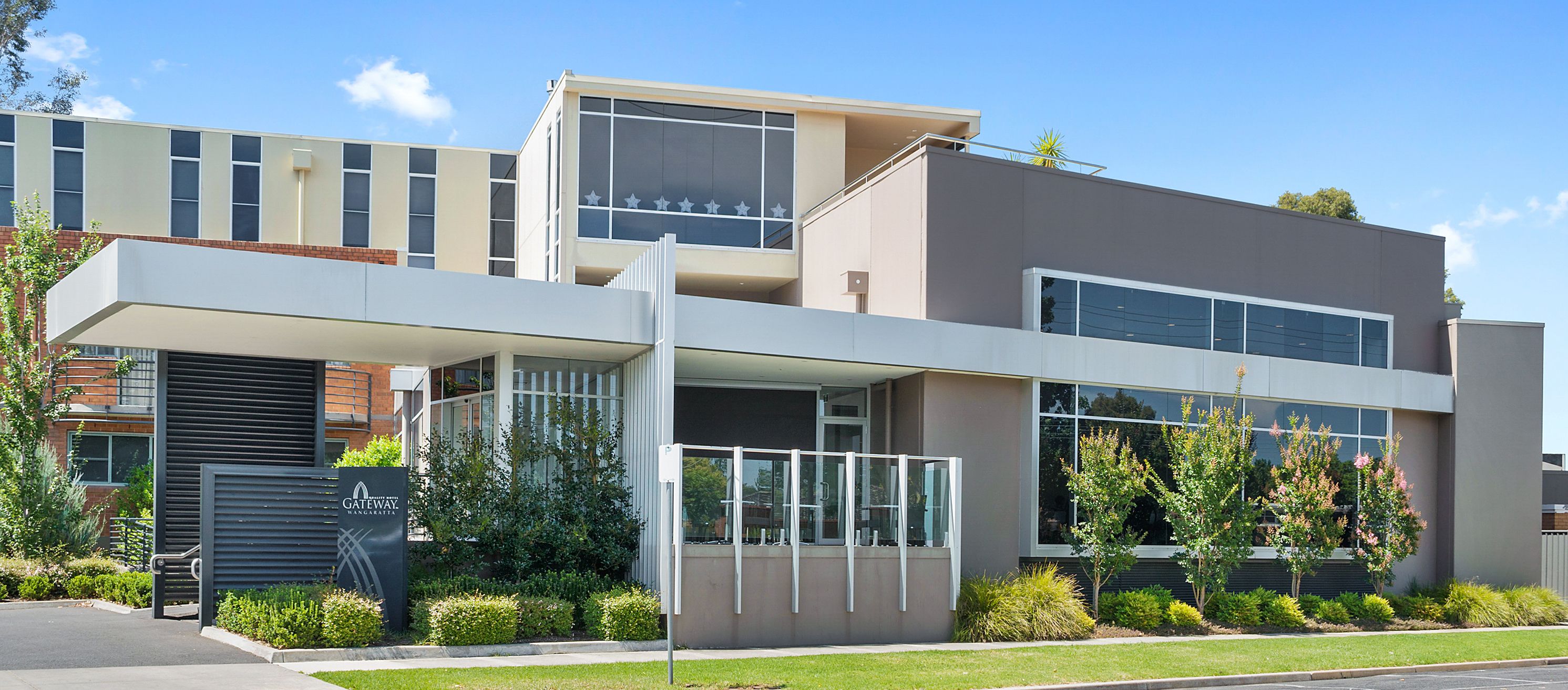 A modern building with a flat roof, large windows, and a covered entrance area.