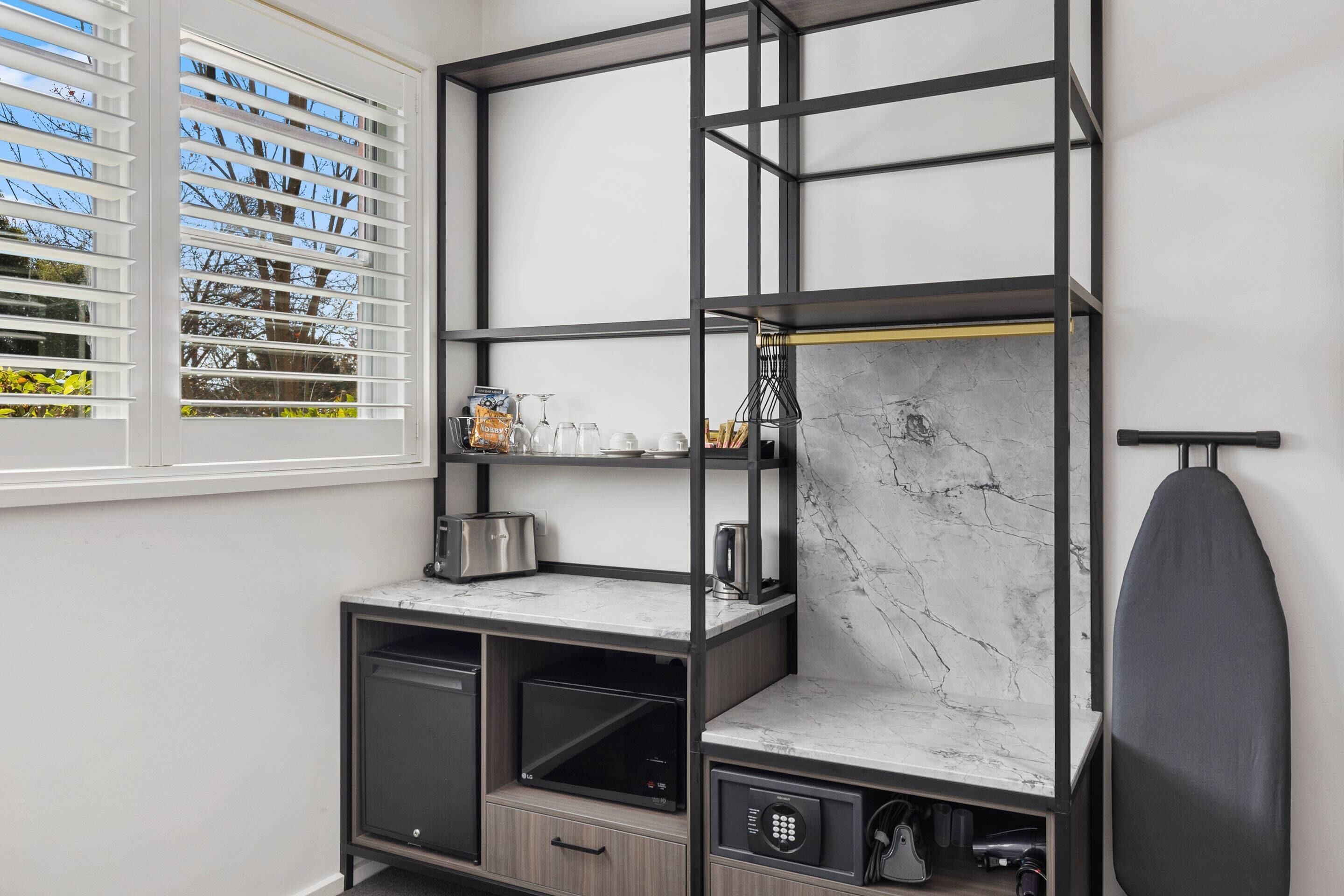 Una cocina moderna con electrodomésticos integrados, un salpicadero de mármol y una ventana con persianas.