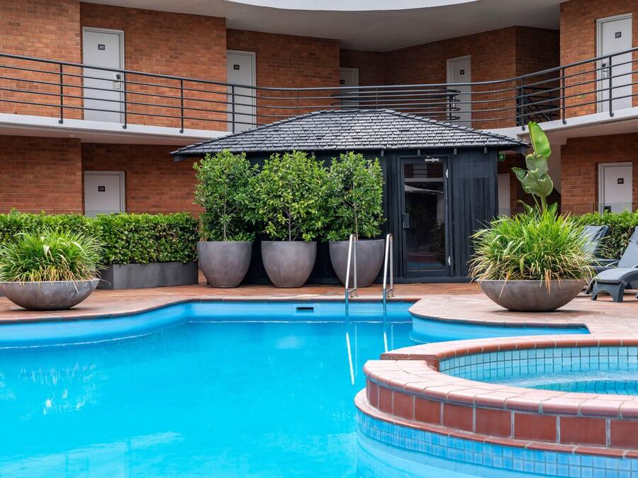 Una piscina amb mur de maó i plantes en testos.