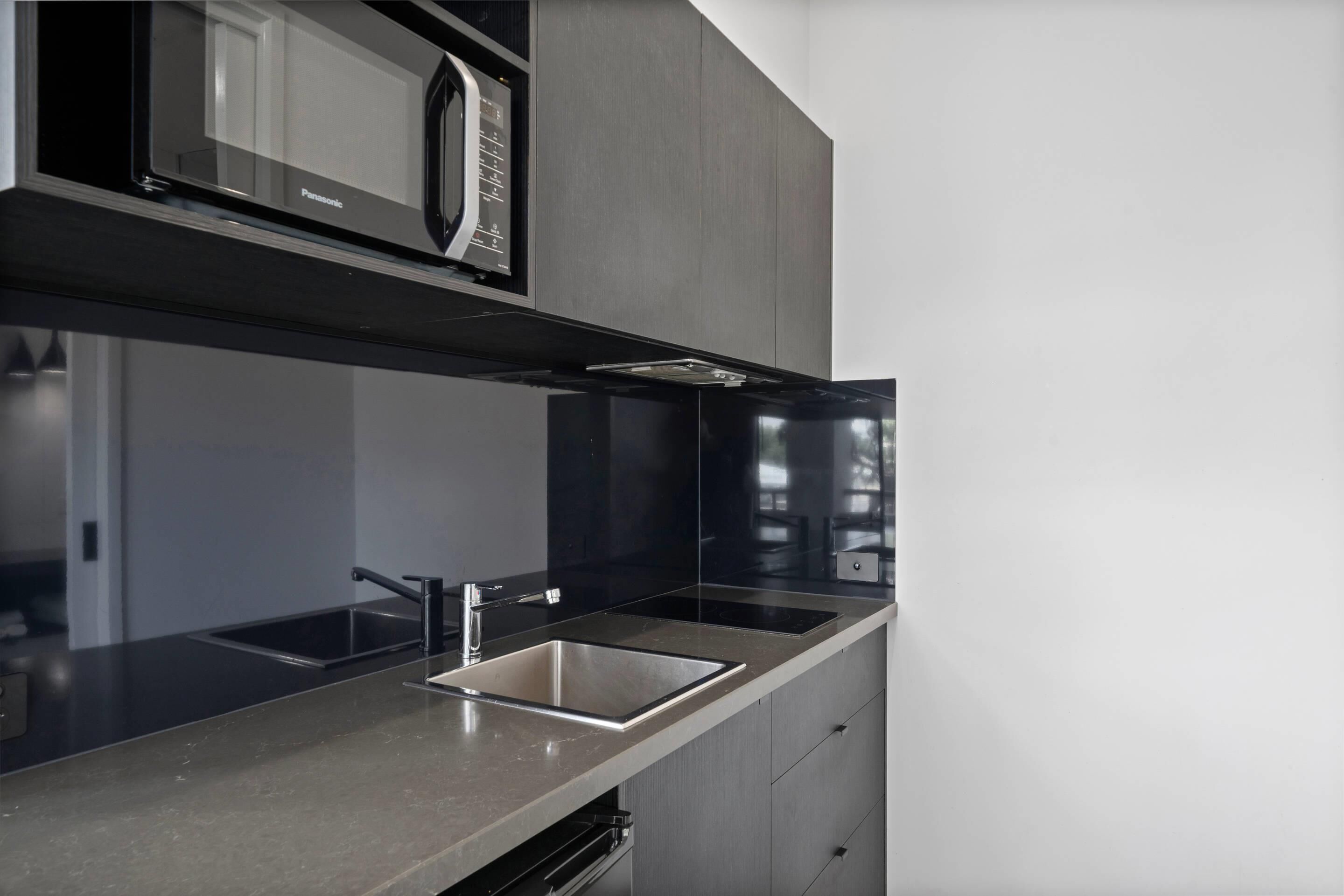 A modern kitchen with a built-in microwave, stainless steel sink, and a sleek countertop.