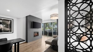 A modern living room with a fireplace, a flat-screen TV, and a dining area with a table and chairs. - Quality Hotel Wangaratta Gateway (Wangaratta)