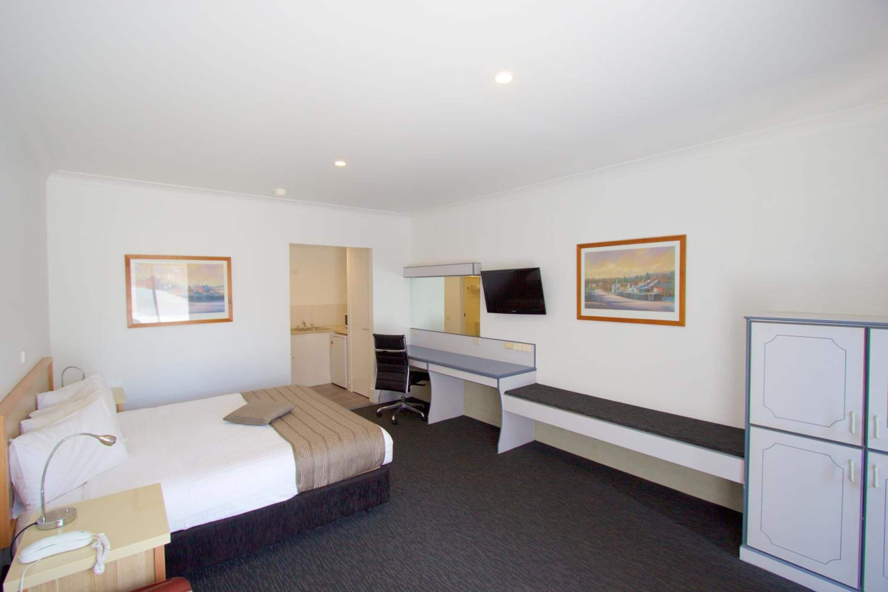 A hotel room with a bed, desk, and wardrobe.