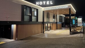 Una entrada moderna de hotel con un letrero que dice "HOTEL GARDEN LODGE SYDNEY" y un número de calle visible "17-23".