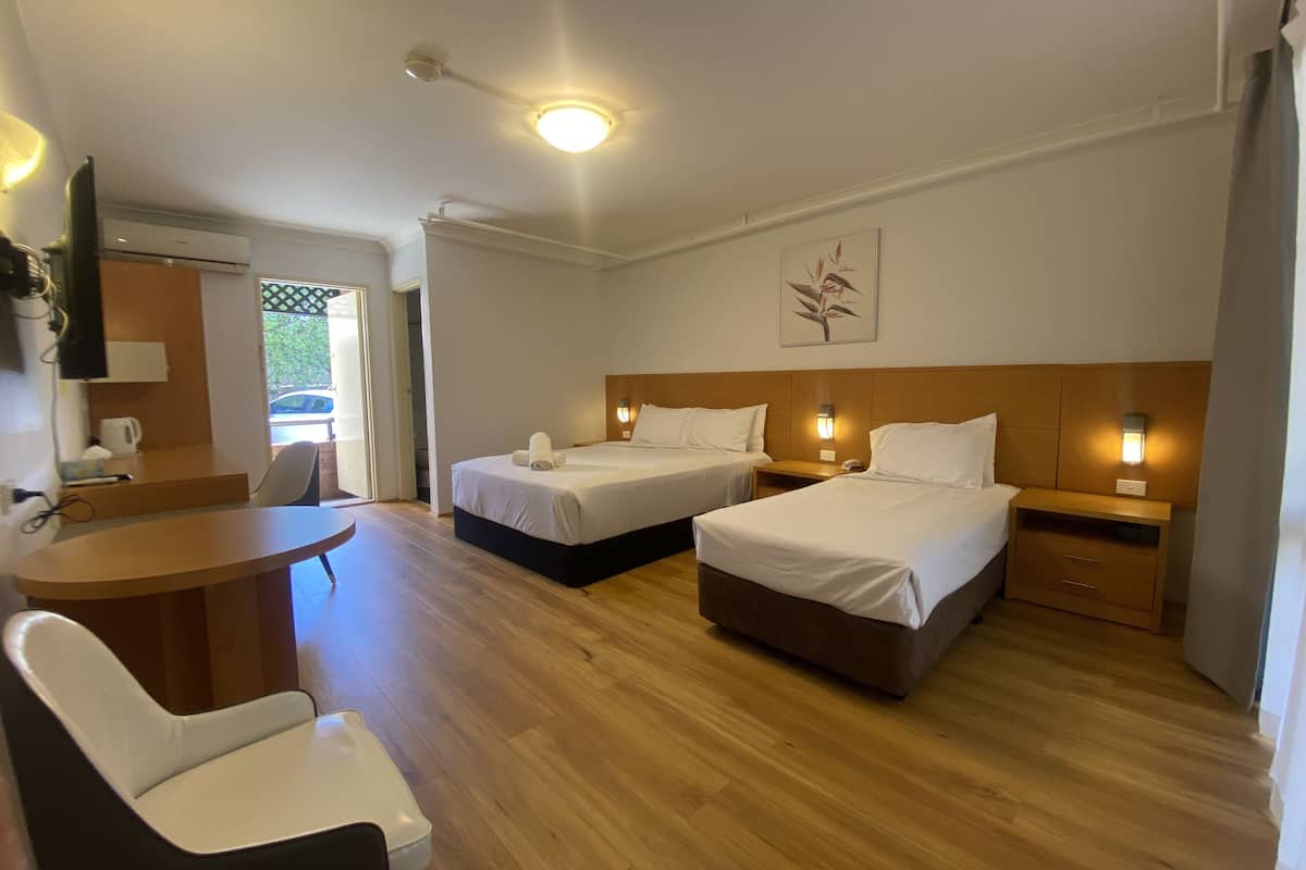 A hotel room with two beds, a desk, a chair, and a small table.