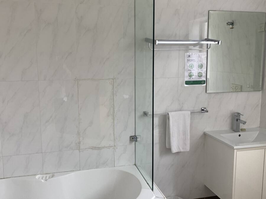 A modern bathroom with a glass-enclosed shower, a freestanding bathtub, a white vanity with a mirror, and a towel rack.