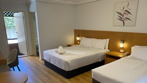 Una habitación de hotel con dos camas, suelo de madera, un escritorio y una silla.