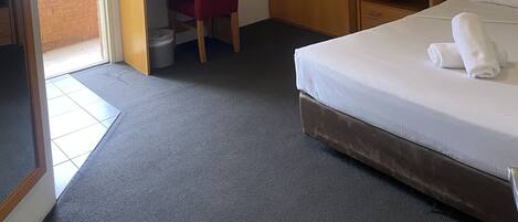 Habitación de hotel con cama, escritorio, silla, armario y aire acondicionado.