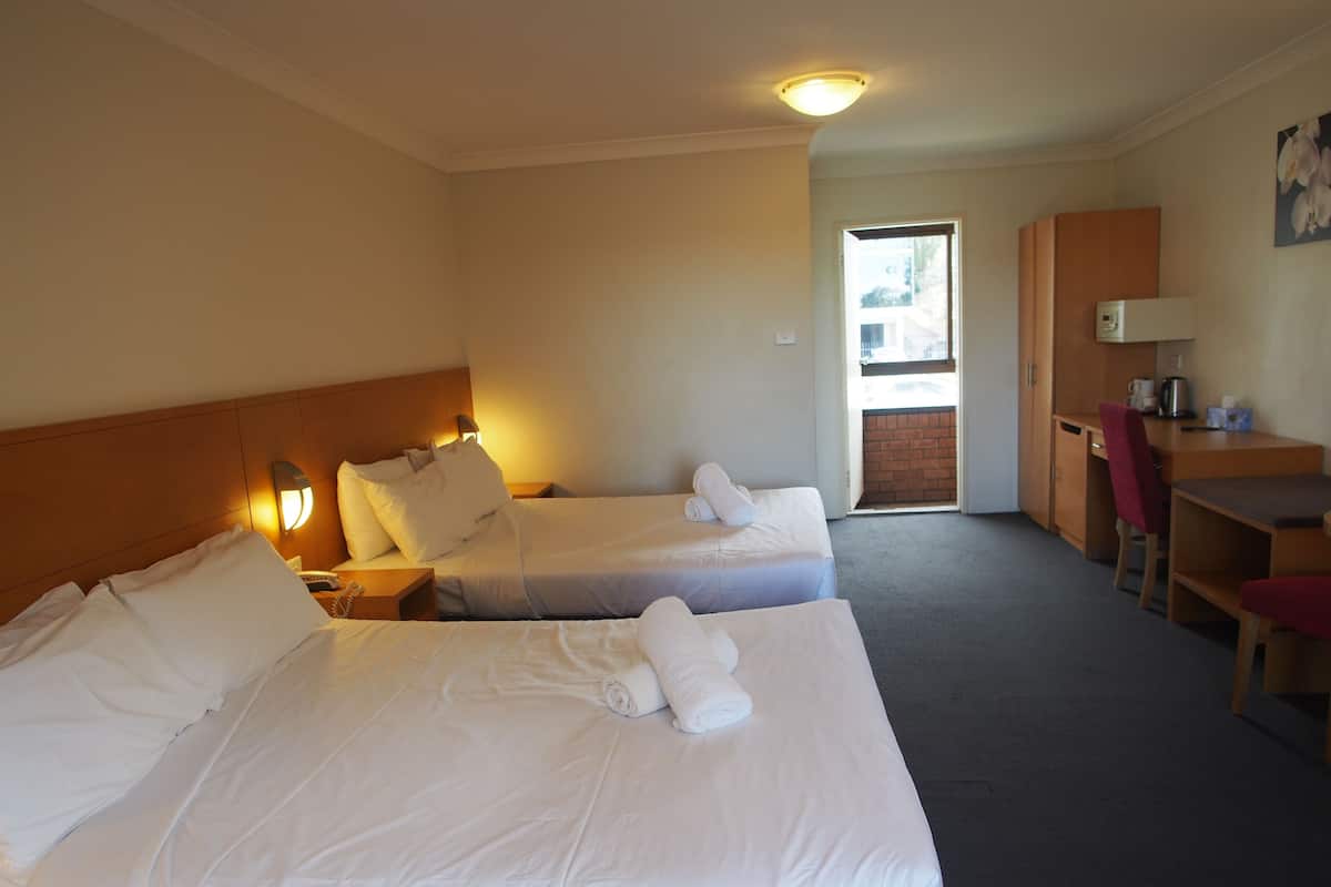 A hotel room with two beds, a desk, and a chair.