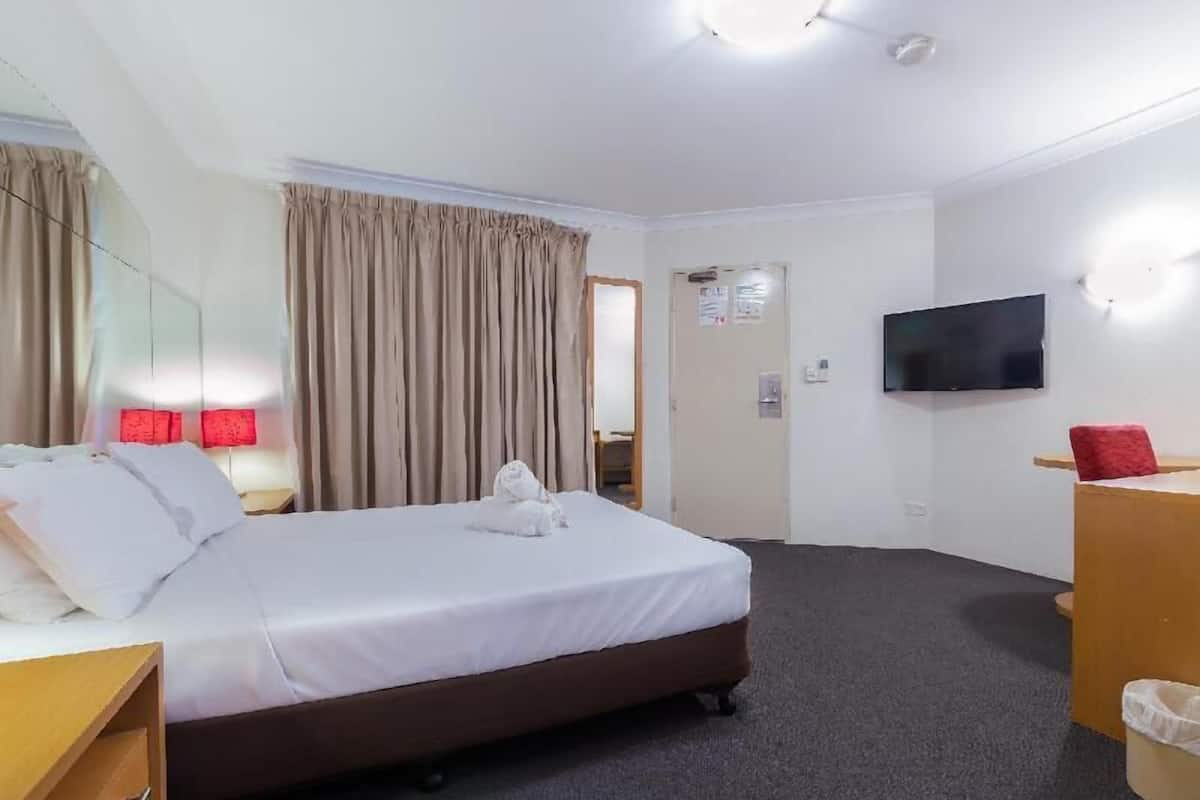 A hotel room with a bed, a TV, a desk, and a mirror.