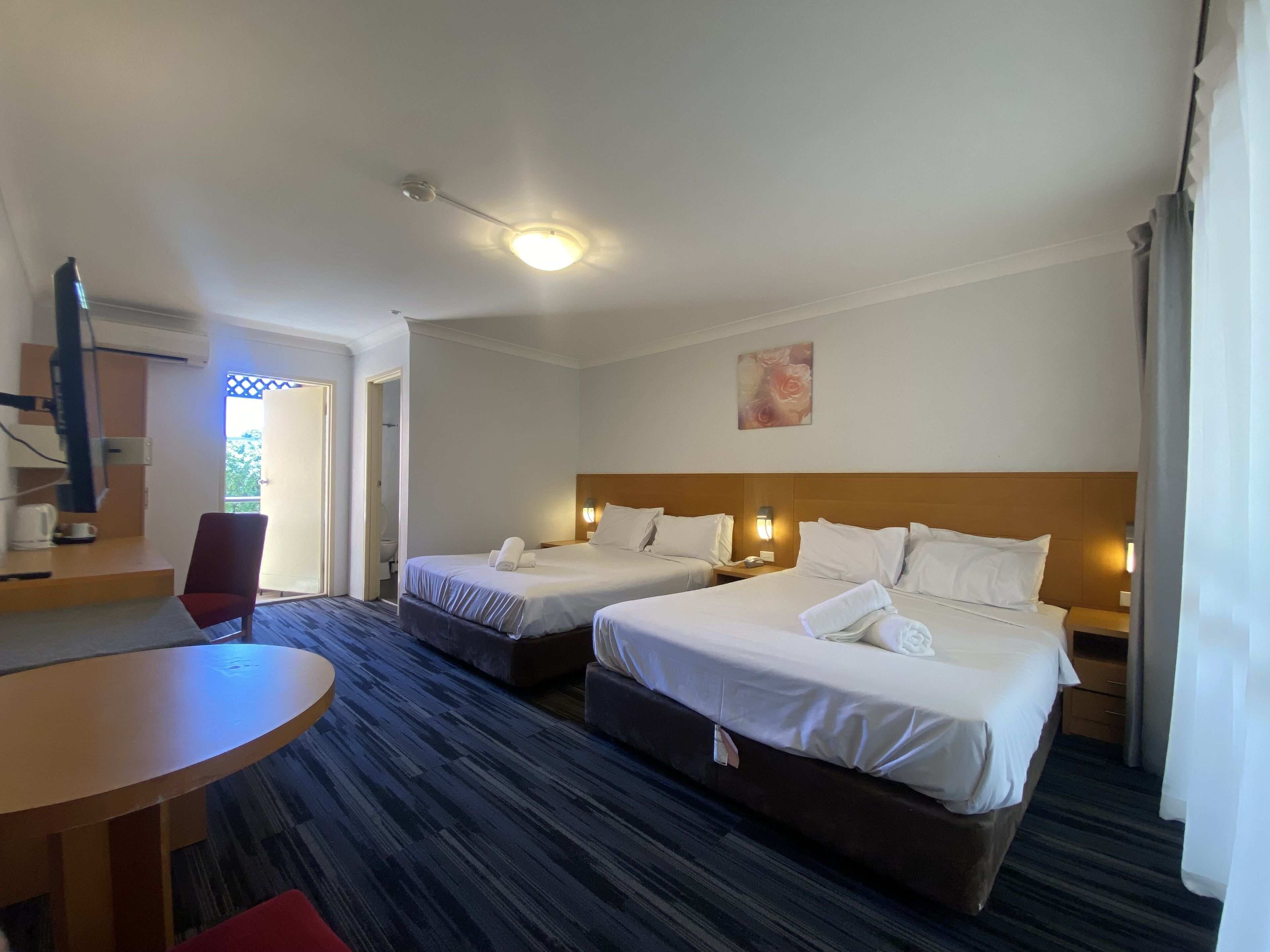 Habitación de hotel con dos camas, un escritorio, una silla y un ventilador de techo.