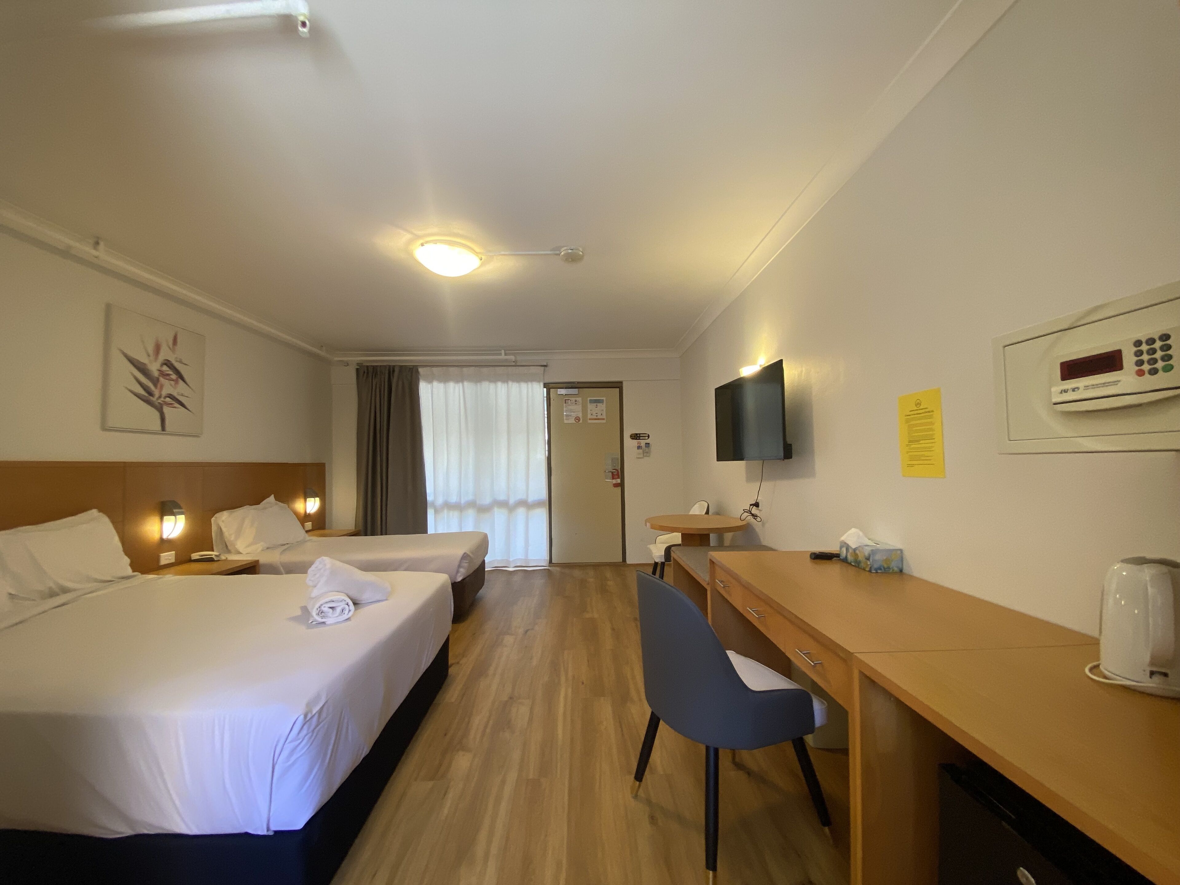 Habitación de hotel con dos camas, un escritorio, una silla, un televisor y una cafetera.