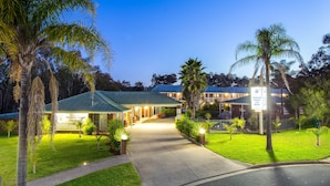 A resort with a covered entrance, well-lit pathways, and lush greenery.
